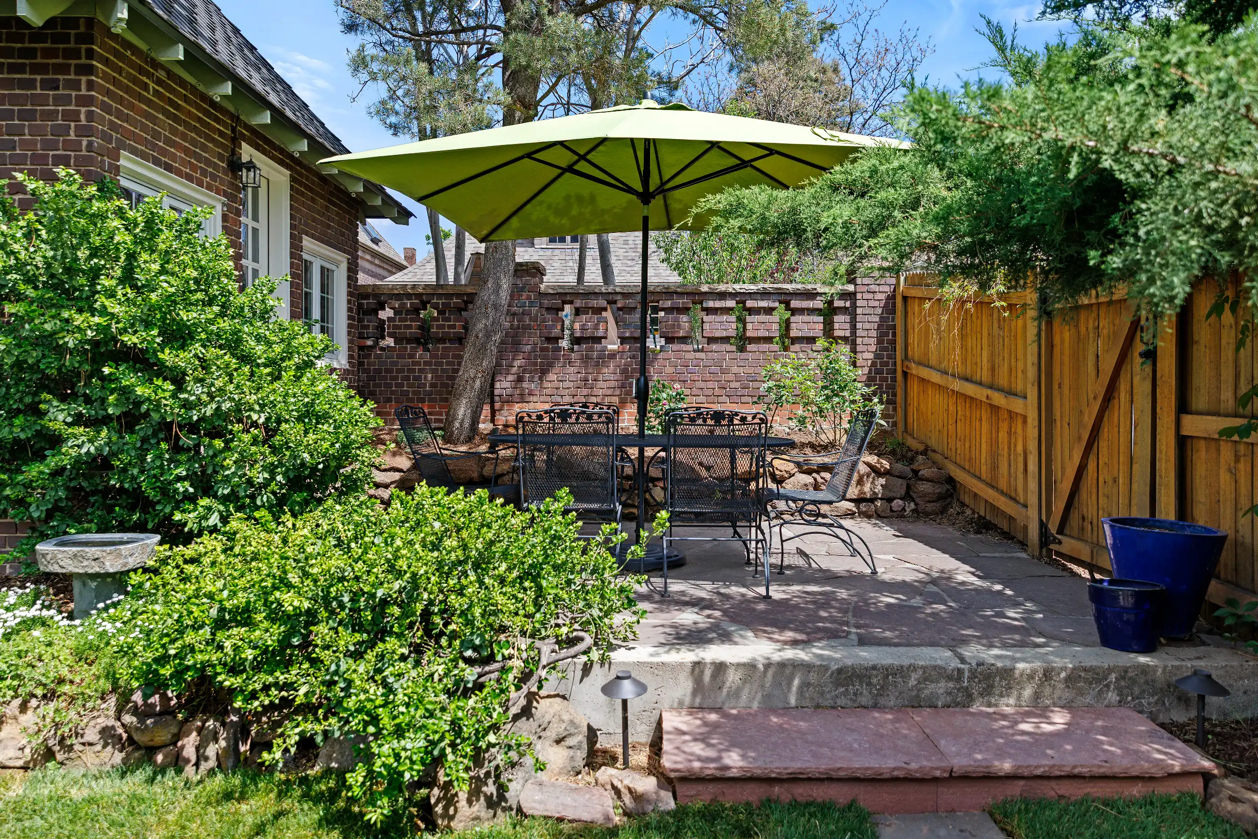 Stone patio with an outdoor dining set under a large green umbrella.
