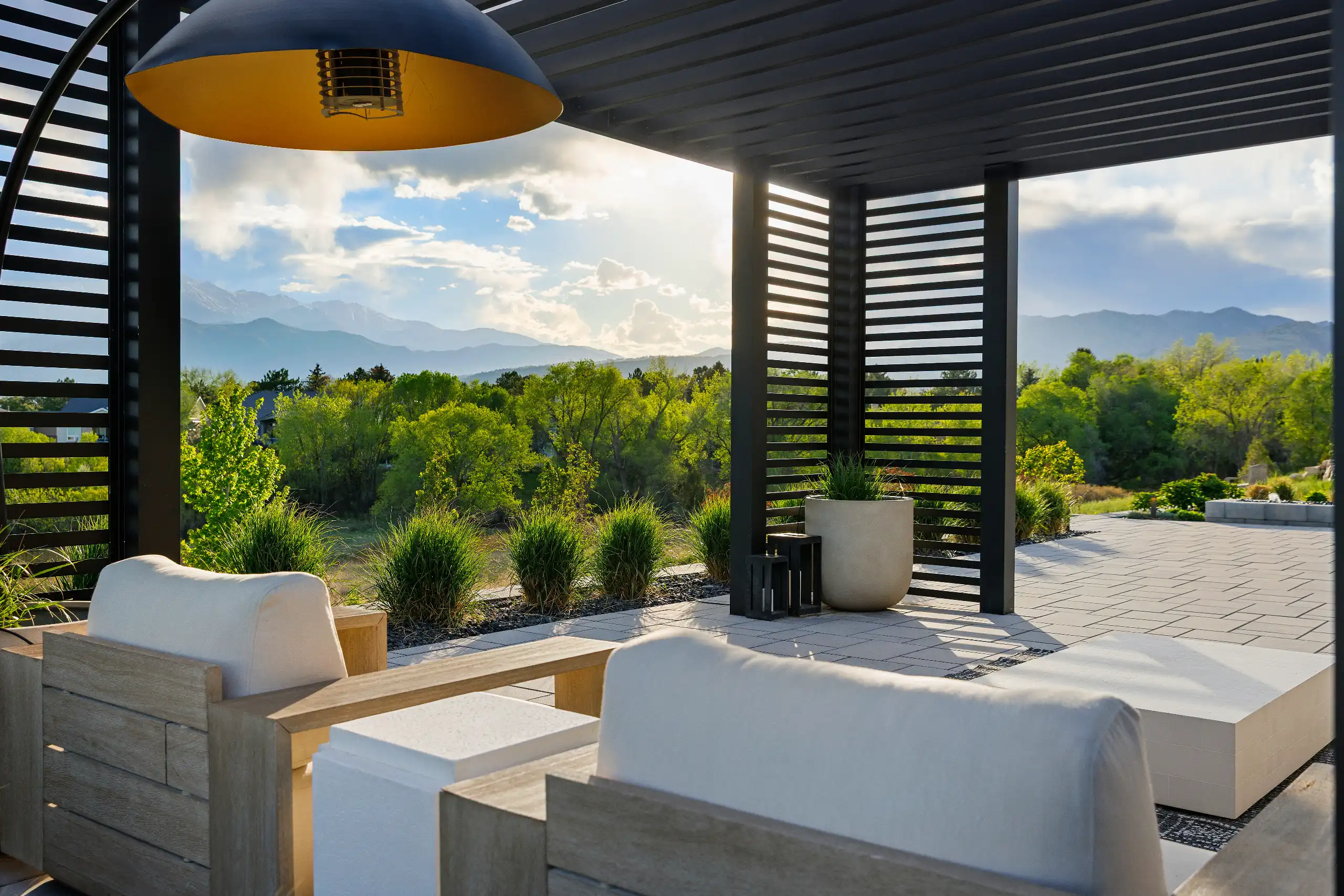 Modern patio under a black slatted pergola featuring a large dome light