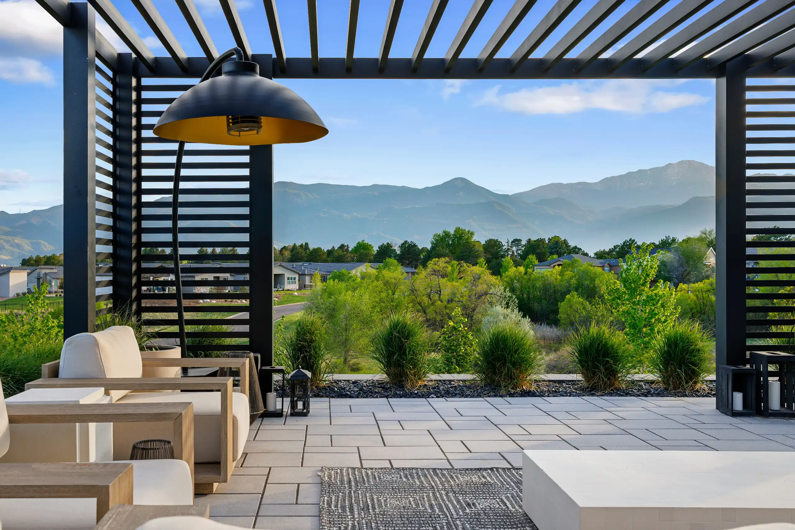 Modern patio under a black slatted pergola featuring a large dome light.